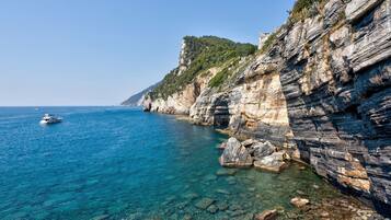 A coastal landscape with clear water, rocky cliffs, and a boat.