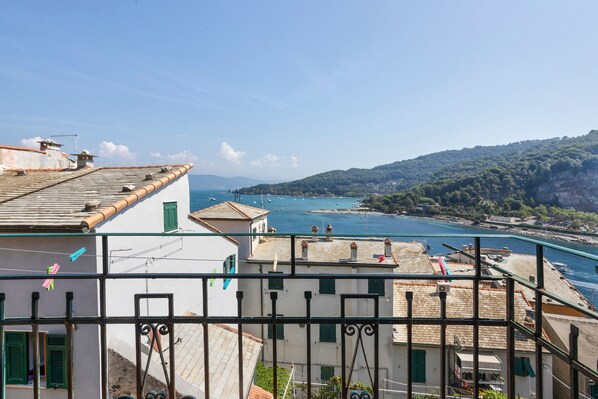 A coastal town with buildings overlooking a bay, featuring balconies and a clear view of the sea.