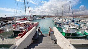 Ein Yachthafen mit vertäuten Booten, eine Holztreppe, die zum Wasser führt, und eine ferne Hügellandschaft.