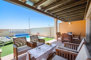 Une terrasse extérieure avec des meubles en bois, une piscine et un ciel dégagé.