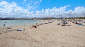 Ein Strand mit blauem Himmel, sandigem Ufer und einer fernen Bergkette.