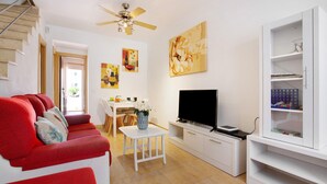 A living room with a sofa, TV, white cabinet, and artwork on the wall.