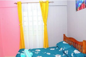 A bedroom with a bed, curtains, and a painting on the wall.
