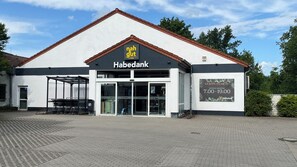 Un bâtiment de type Habendank, doté d’une entrée bien visible, d’une enseigne et d’une zone pavée devant.