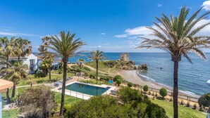 Une propriété située sur la côte, dotée d’une piscine, de palmiers et offrant une vue sur la plage.