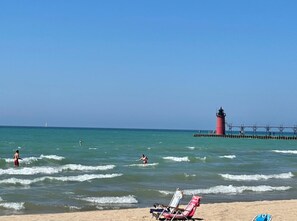 A beach with a lighthouse, waves, and beach chairs. - ❤️The Nest❤️ Shot Walk to Beach, Park, Riverfront & Downtown (South Haven)