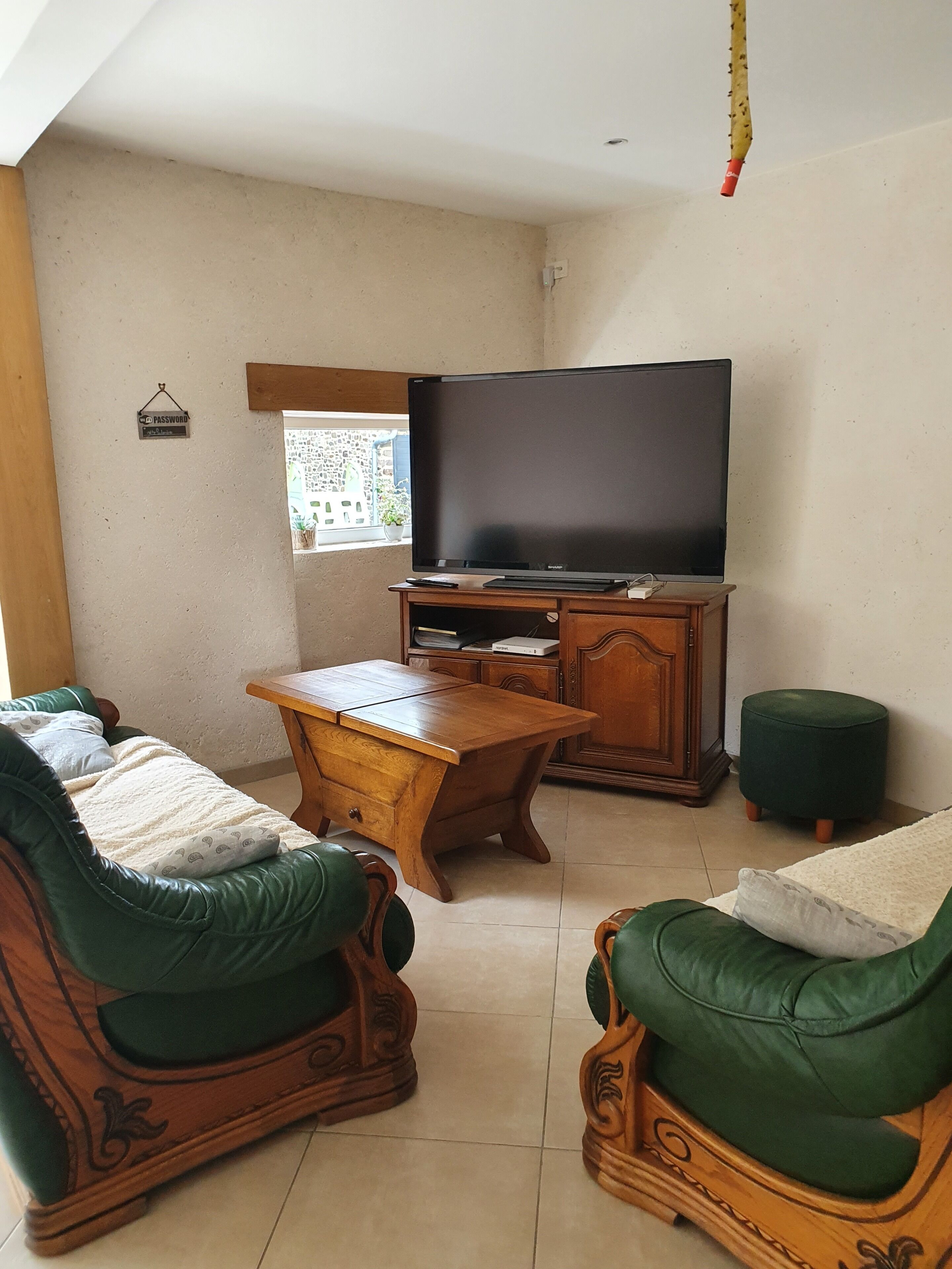 Una sala de estar con televisor, muebles de madera y un ventanal.