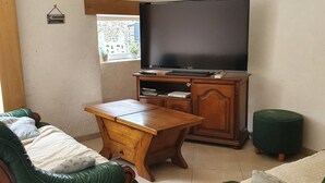 Un soggiorno con televisore, mobili in legno e una finestra.