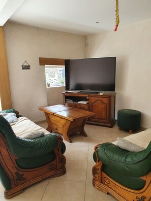 Ein Wohnzimmer mit Fernseher, Holzmöbeln und einem Fenster.