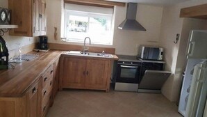 Una cucina compatta con mobili in legno, un lavello, un fornello e un forno a microonde.