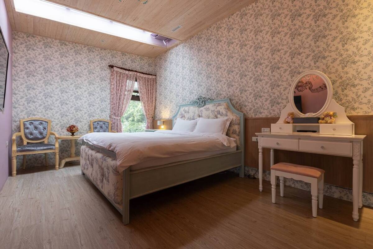 Un dormitorio con una cama, una tocador con espejo y dos sillas.