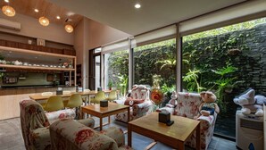 A modern living room with a dining area, large windows, and a view of greenery.