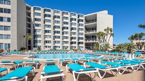A hotel pool area with multiple lounge chairs and a large swimming pool.
