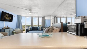 A modern hotel room with a large bed, a dining table, a TV, and a view of the outdoors.