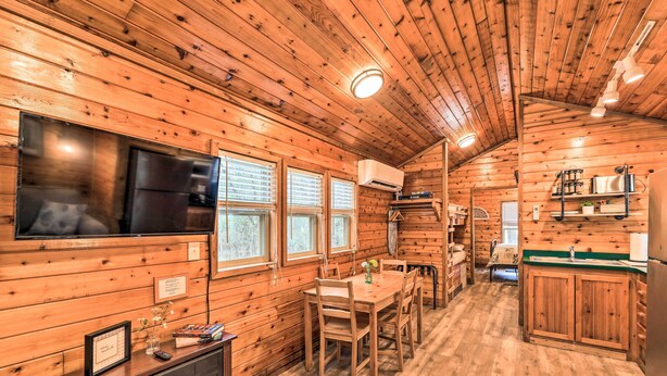L’intérieur d’une cabane en bois comprend un coin repas, une cuisine et un téléviseur fixé au mur.