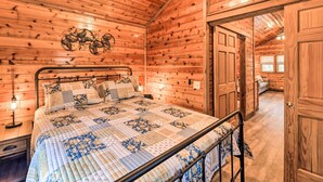 Une chambre aménagée dans une cabane en bois, avec un lit, une table de chevet et un élément décoratif fixé au mur.