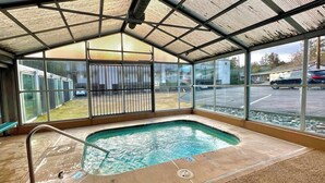A covered outdoor swimming pool with a metal roof, a bench, and a view of a parking lot. - River View Condo- Edge of Downtown (Bend)