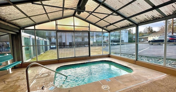 A covered outdoor swimming pool with a metal roof, a bench, and a view of a parking lot. - River View Condo- Edge of Downtown (Bend)