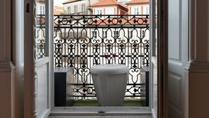 A balcony with ornate black metal railings, a white pedestal sink, and a view of buildings with red-tiled roofs. - SKY DE LOIOS - Charming apartment with balcony (Porto)
