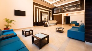 Eine moderne Lobby mit blauen Sofas, einem Empfangsbereich und einem großen Fenster.