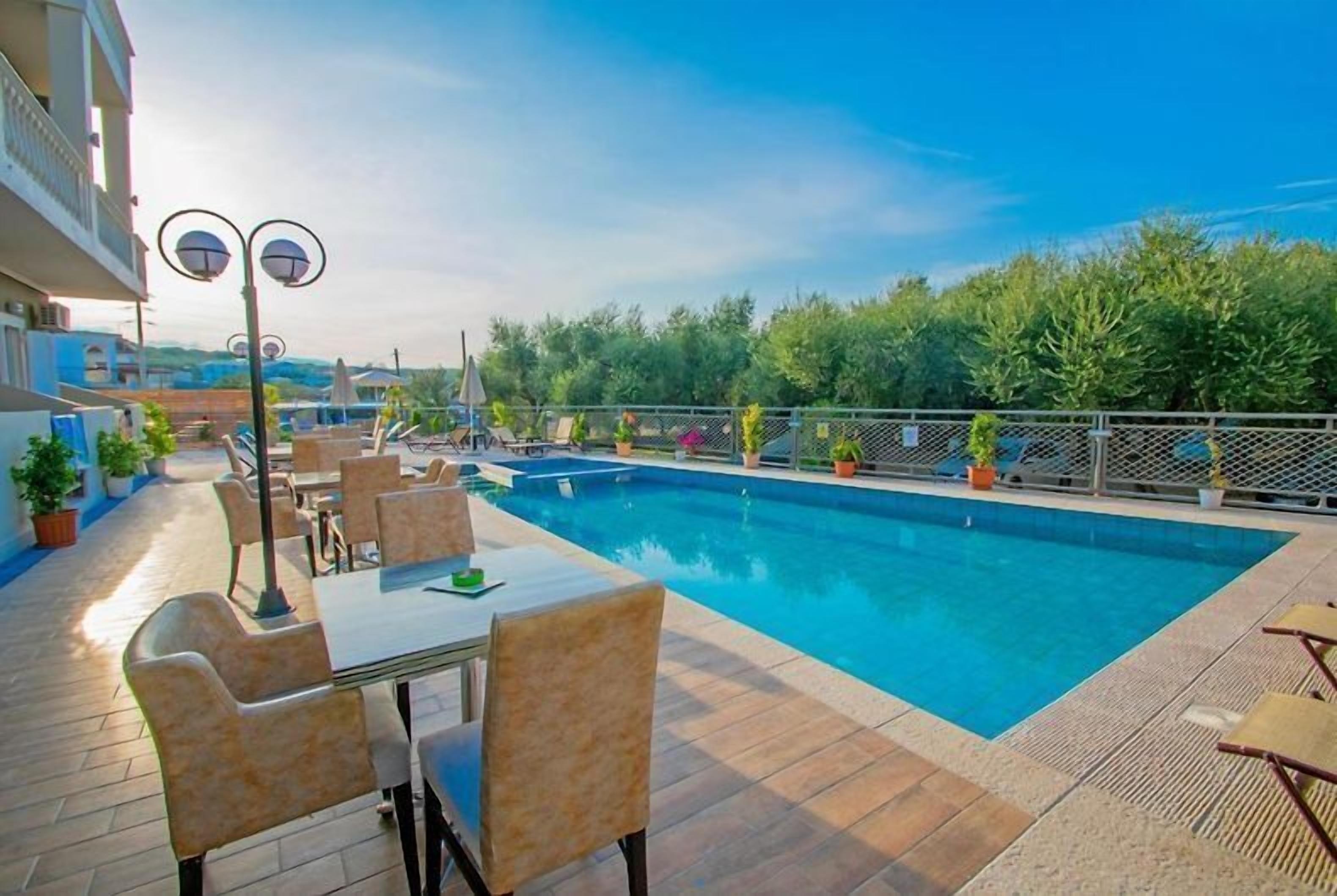 Ein Poolbereich mit Tisch und Stühlen, umgeben von Topfpflanzen und einem Zaun.