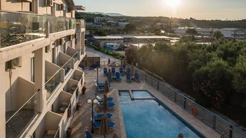 Ein Hotelpoolbereich mit Liegestühlen und Sonnenschirmen, mit freiem Blick auf die umliegende Landschaft und einem Pool mit einem Rettungsring.