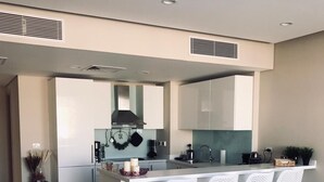 A modern kitchen with a central island, white bar stools, and a cowhide rug on the floor.