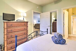 A bedroom with a bed, a dresser, a television, and a door leading to another room. - Access to 7 Pools: Myrtlewood Golf Condo! (Myrtle Beach)