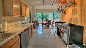 Una cucina moderna con mobili in legno, lavastoviglie e zona pranzo con tavolo e sedie.