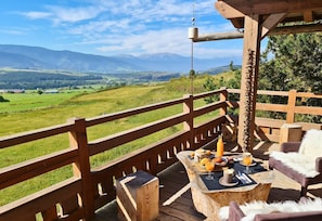 A wooden deck with a table set for breakfast, overlooking a green valley and mountains. - Chalet Hanadama Collection Perles (Bolquère)