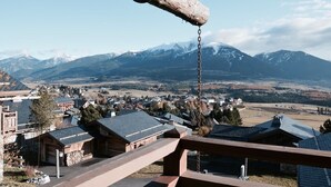 Une balançoire en bois donnant sur une ville, avec des montagnes enneigées en arrière-plan.