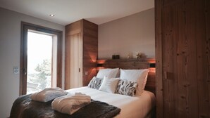Une chambre avec un grand lit, une tête de lit en bois et une vue par la fenêtre.