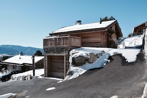 A wooden cabin with a stone entrance, a snow-covered roof, and a view of mountains in the background. - Chalet Hanadama Collection Perles (Bolquère)