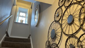 Un escalier doté d’une rampe, de marches recouvertes de moquette et d’un mur orné de miroirs en forme de roues de bicyclette décoratives en métal.