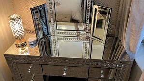 Une coiffeuse dotée d’un grand miroir, de nombreux tiroirs et d’une lampe décorative.