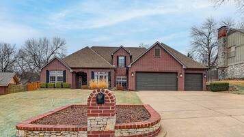 A two-story brick house with a stone fireplace, a garage, and a well-maintained lawn.