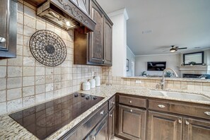 Una cocina con isla central, armarios de madera oscura, salpicadero de azulejos y estufa empotrada.