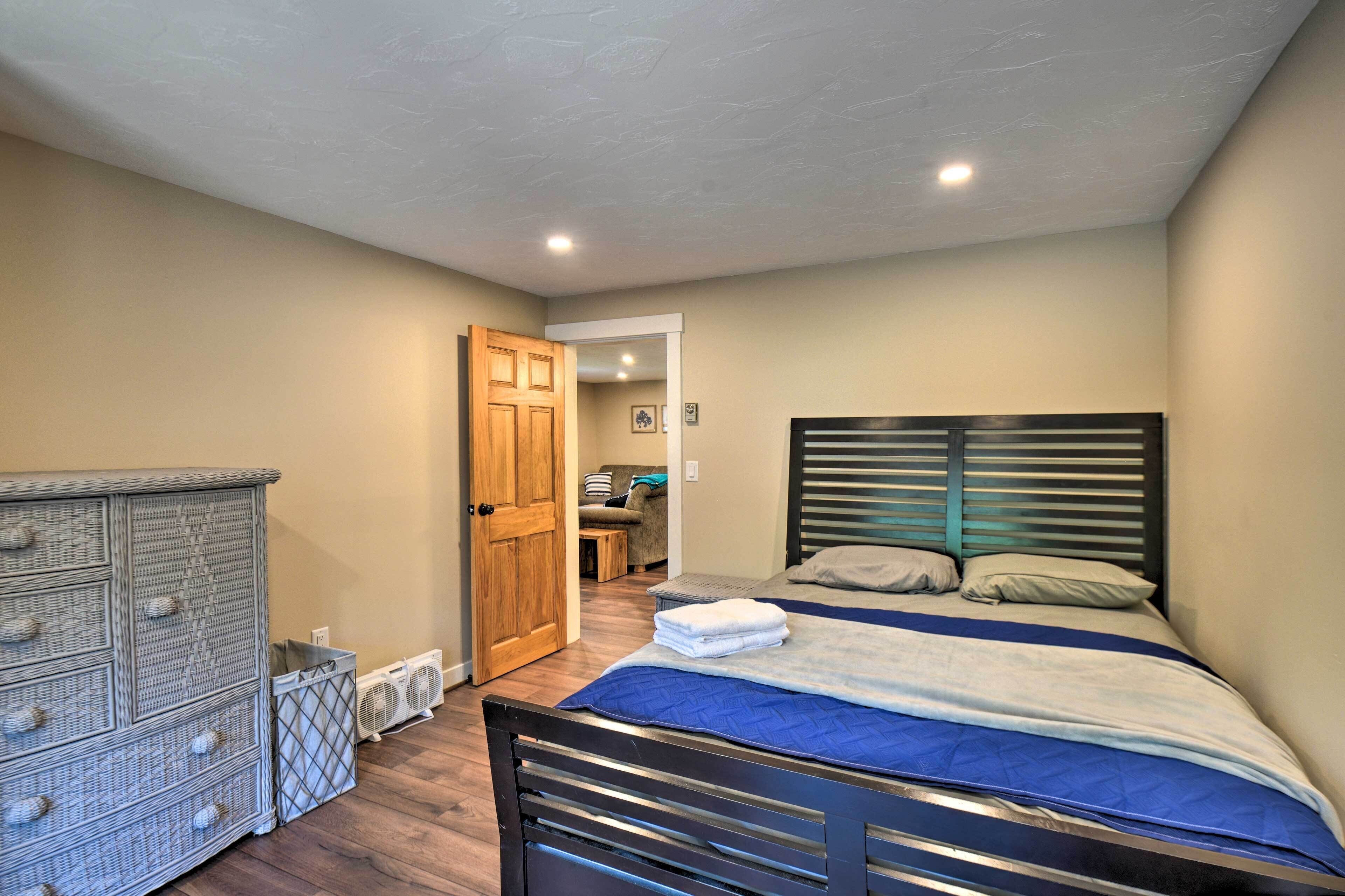 Une chambre à coucher comprenant un lit, une commode et une porte donnant sur une autre pièce.