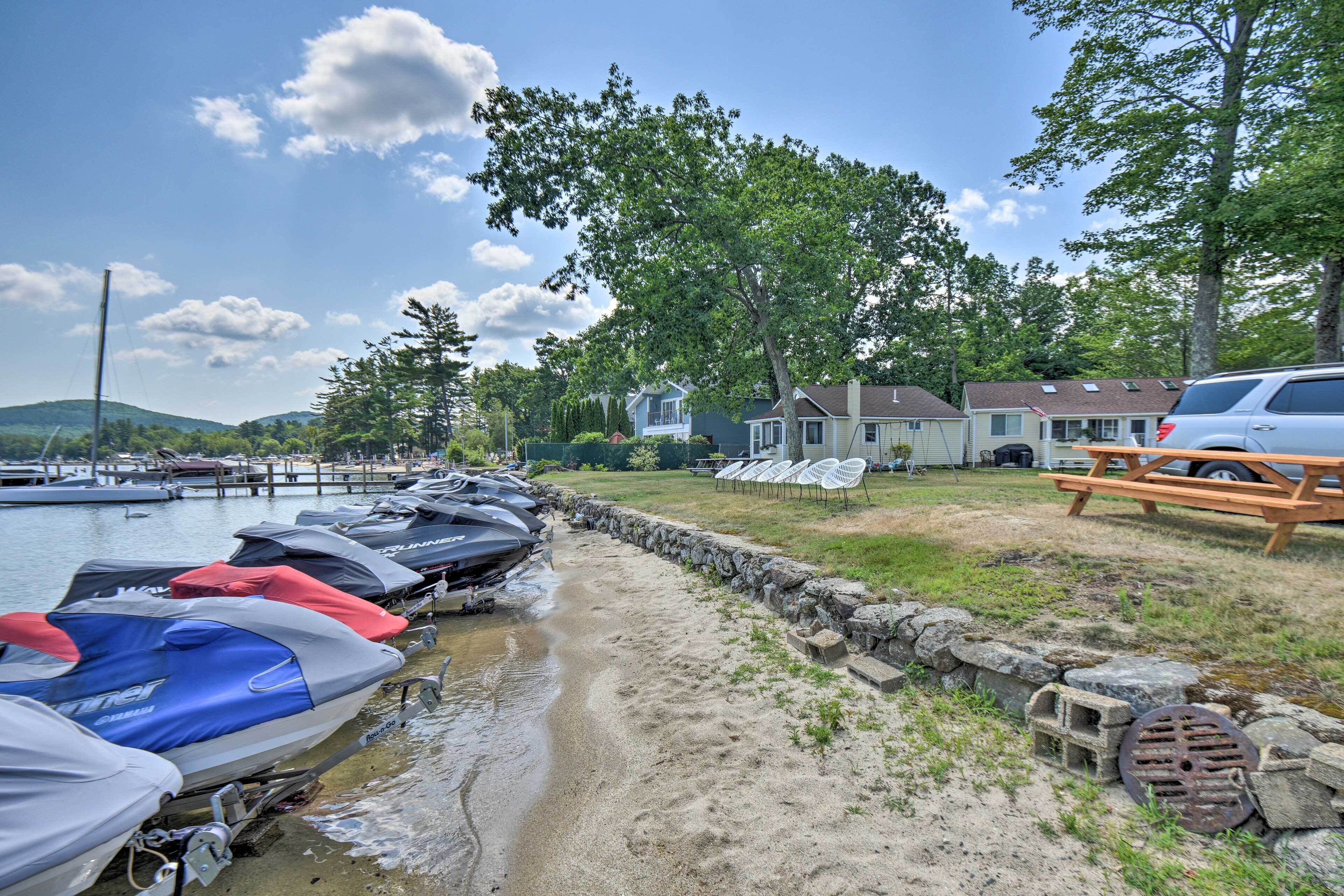 Un port de plaisance avec des jet-skis amarrés, une table de pique-nique et des maisons en arrière-plan.