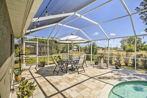 A covered patio area with a pool, outdoor furniture, and potted plants.