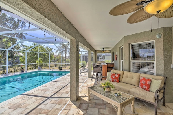 A covered patio with a pool, outdoor furniture, and a ceiling fan.