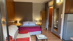 Una habitación de hotel compacta con cama, una mesita, un sofá y un espejo.