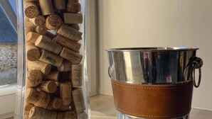 A clear glass vase filled with wine corks and a metal bucket with a handle. - Charming renovated house with private terrace and garden (Rives-d'Andaine)