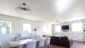 A modern living room with a dining area, a large window, and a brick floor. - Charming cottage for 6 near Angers, countryside tranquility (Corzé)