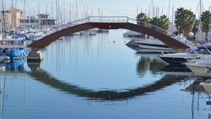 A marina with boats docked under a bridge.