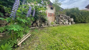 Een tuin met paarse bloemen, een houten hek en een huis met een rode deur.