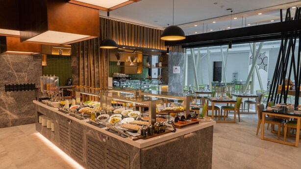 A buffet area with a marble counter, various food items, and a seating area with tables and chairs. - Al Khoory Courtyard Hotel (Dubai)