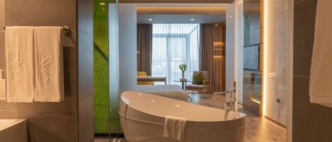 Un baño moderno con una bañera independiente, cabina de ducha con paredes de vidrio y una zona de comedor visible con una mesa y sillas.