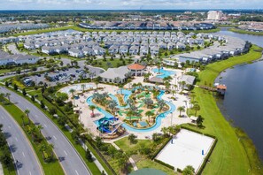 Vista aérea de una zona residencial con piscina central, carreteras conectadas y una gran extensión de agua.