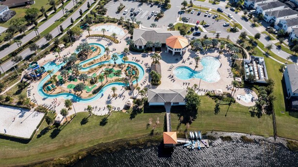 An aerial view of a resort with multiple swimming pools, a water park, and a clubhouse.